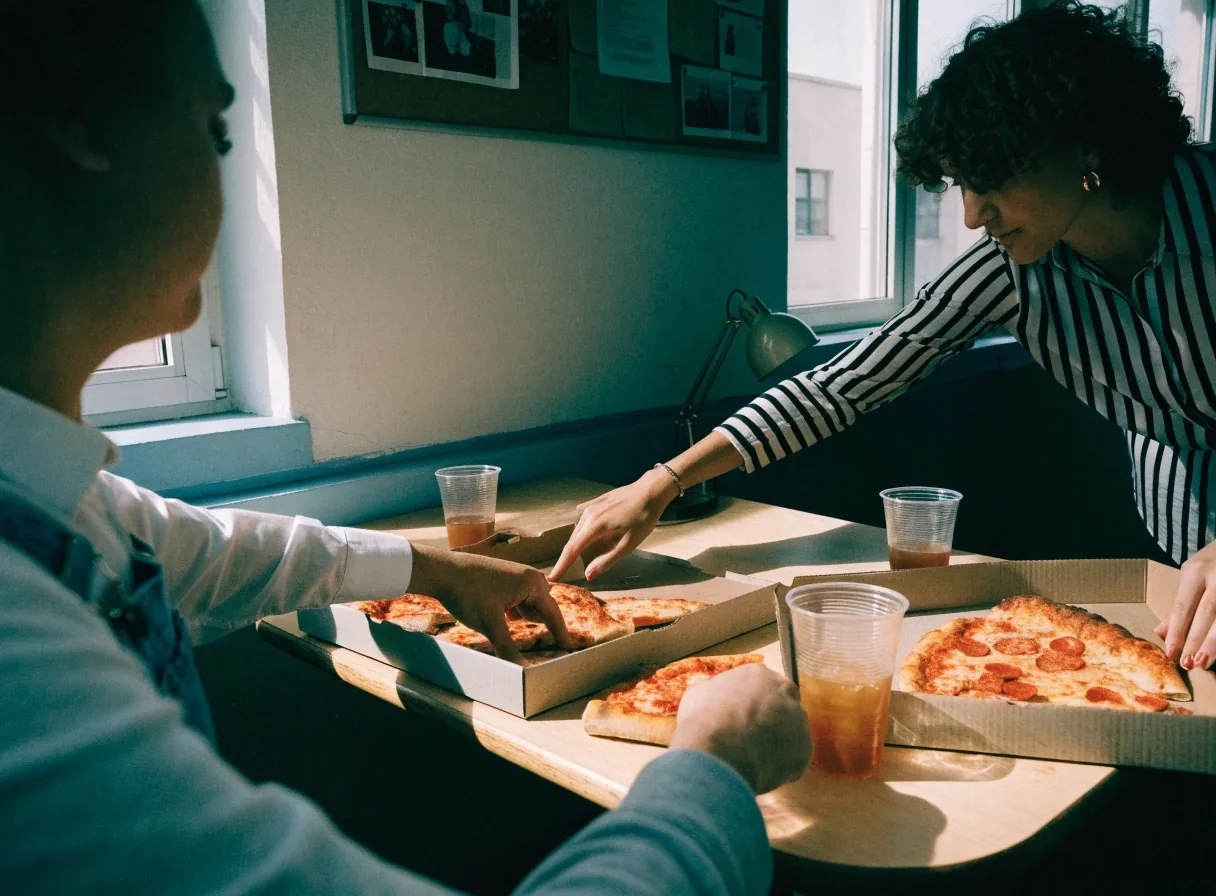 Small office lunch sharing pizza from open boxes